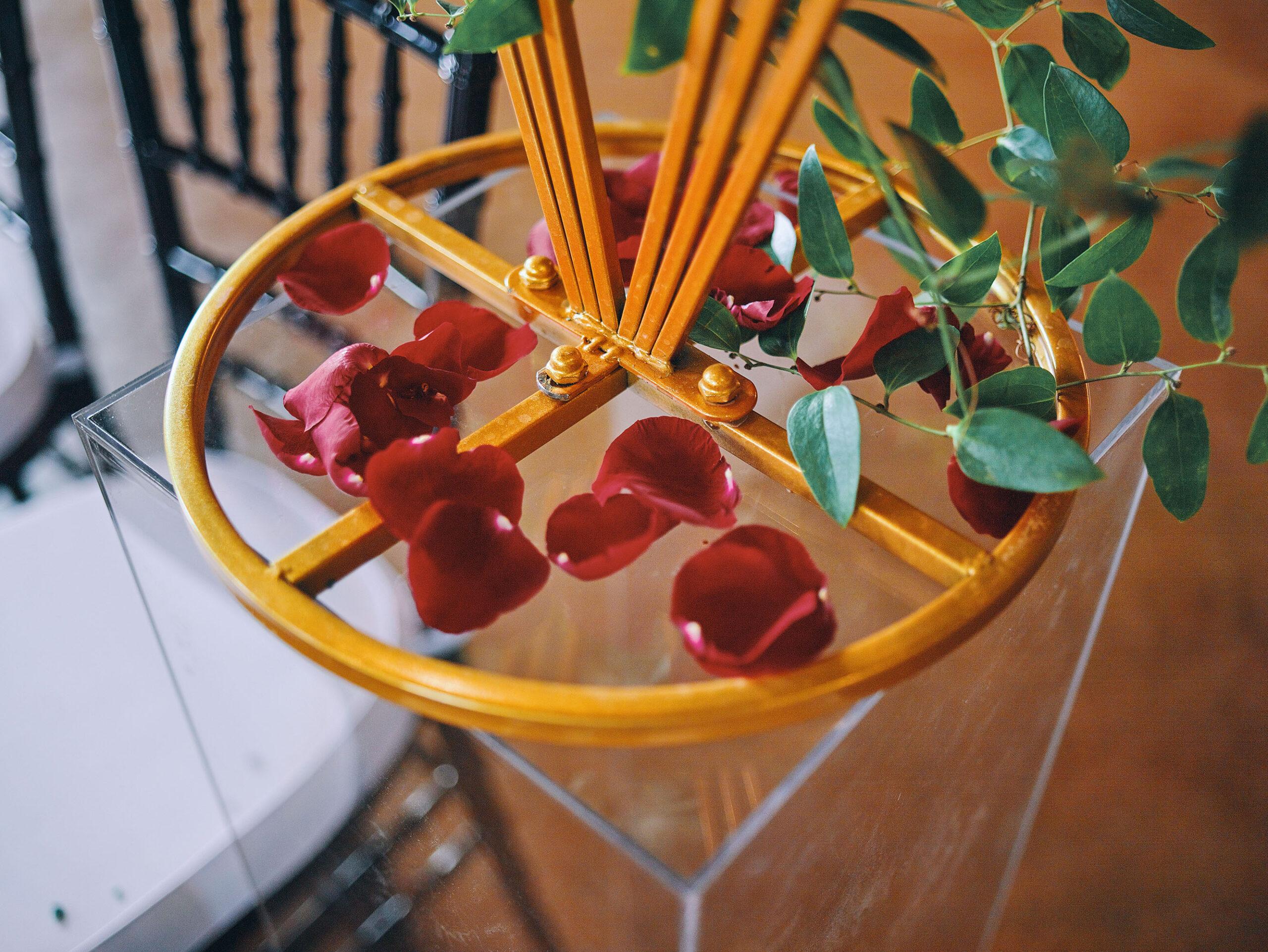 luxurious indoor wedding ceremony decor design, with a large red, yellow, and orange floral designs and a colorful bridal bouquet.