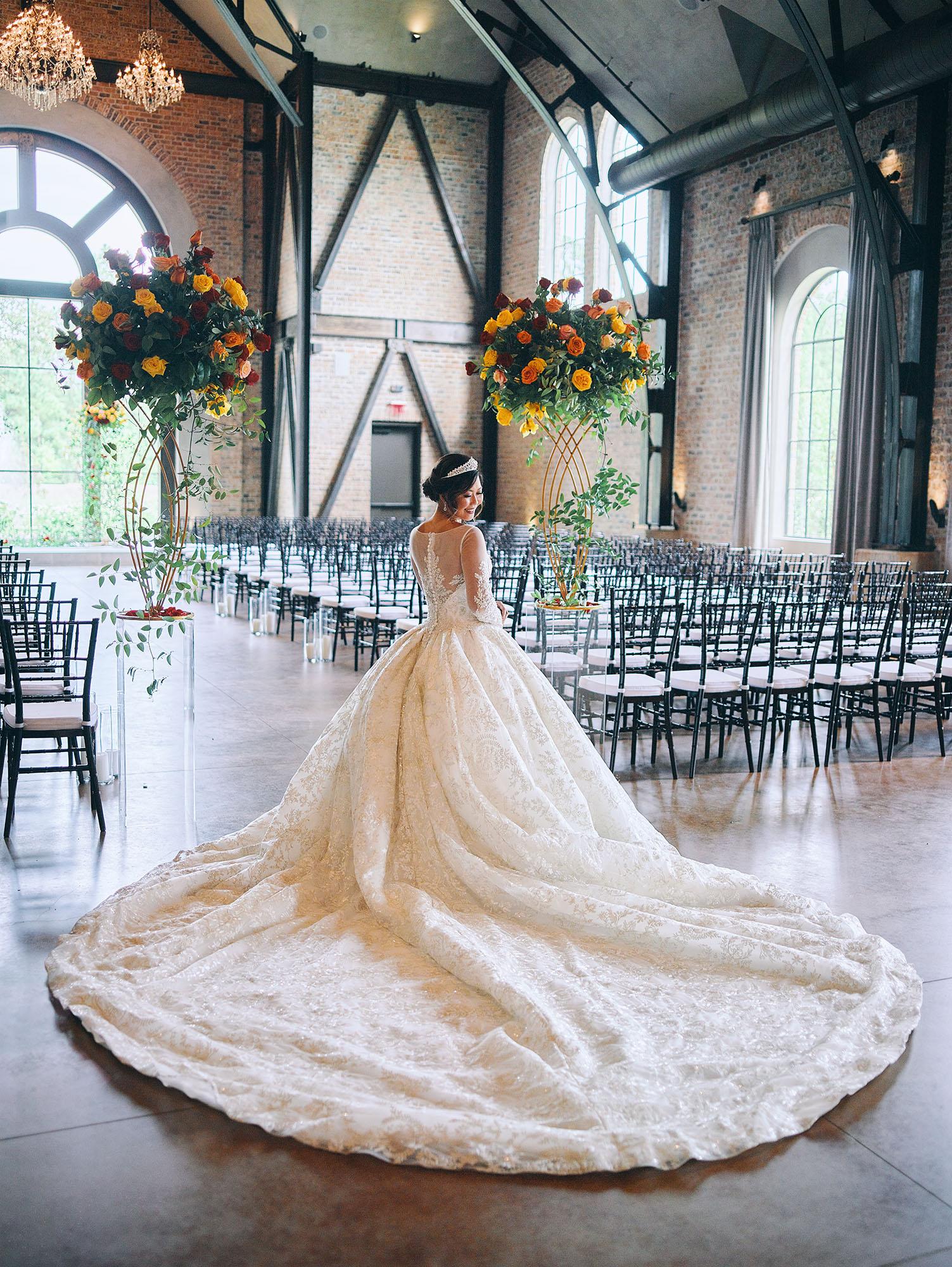 luxurious indoor wedding ceremony decor design, with a large red, yellow, and orange floral designs and a colorful bridal bouquet.