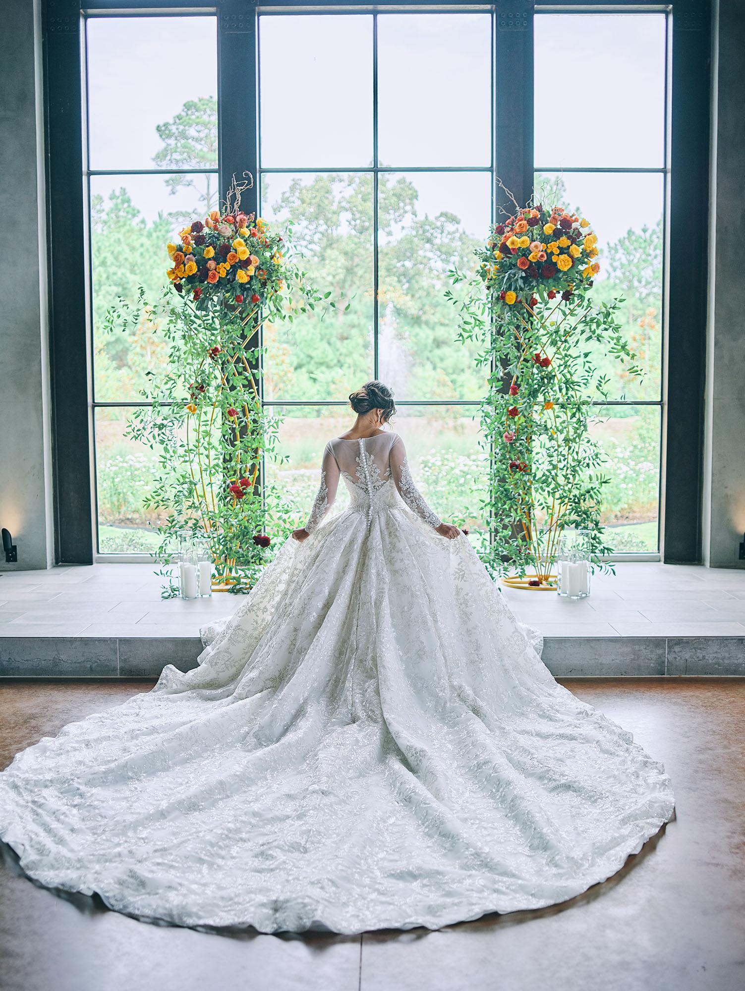 luxurious indoor wedding ceremony decor design, with a large red, yellow, and orange floral designs and a colorful bridal bouquet.