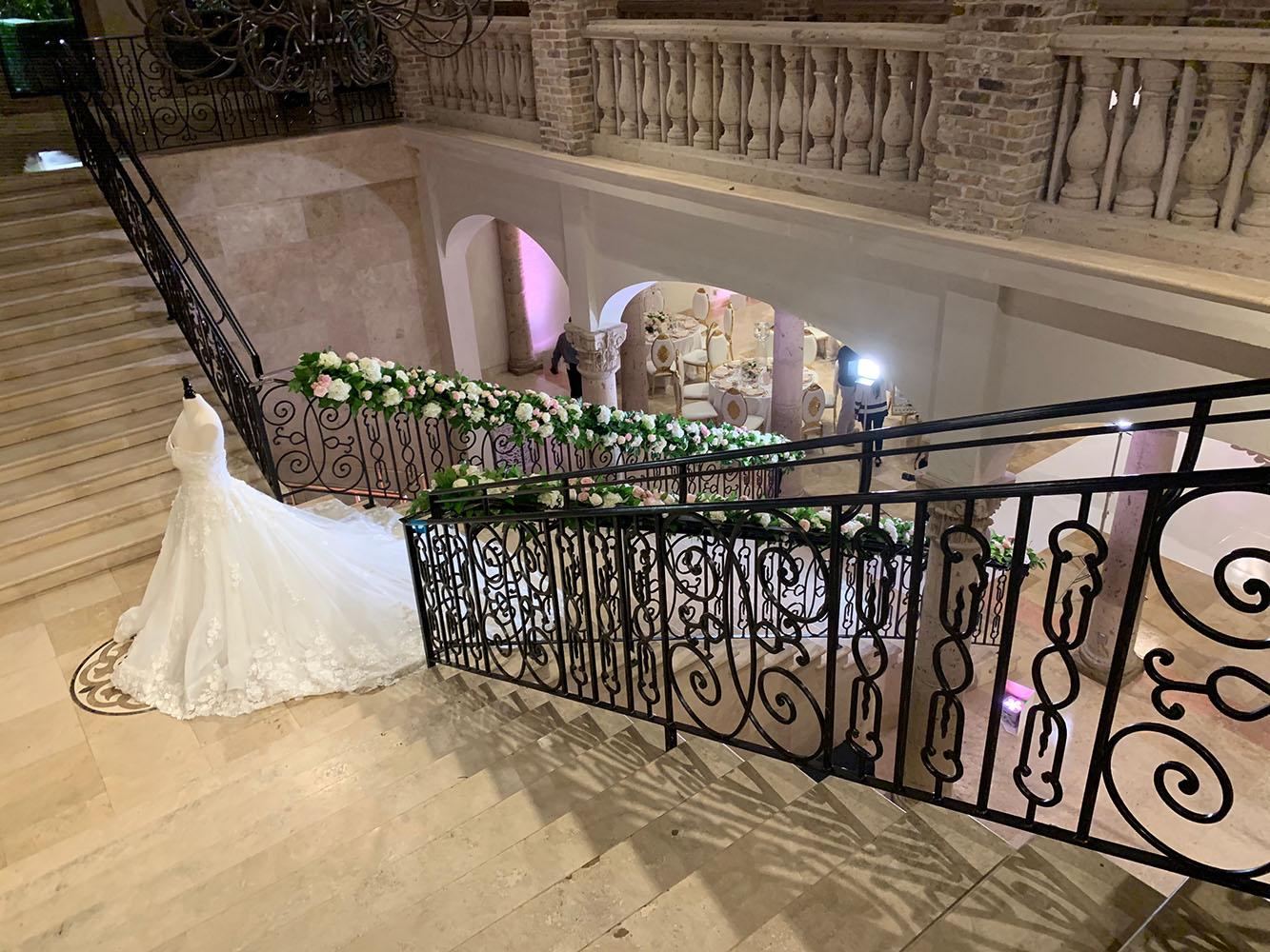 The reception decor featured gold crystal serpentine tables with floral runners, a white and gold dance floor with a custom monogram, a crystal gold cake table, and tall clear vase centerpieces.