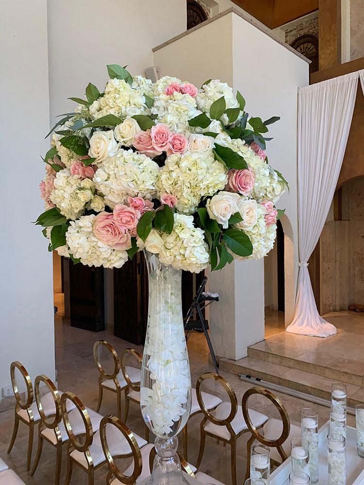 The reception decor featured gold crystal serpentine tables with floral runners, a white and gold dance floor with a custom monogram, a crystal gold cake table, and tall clear vase centerpieces.