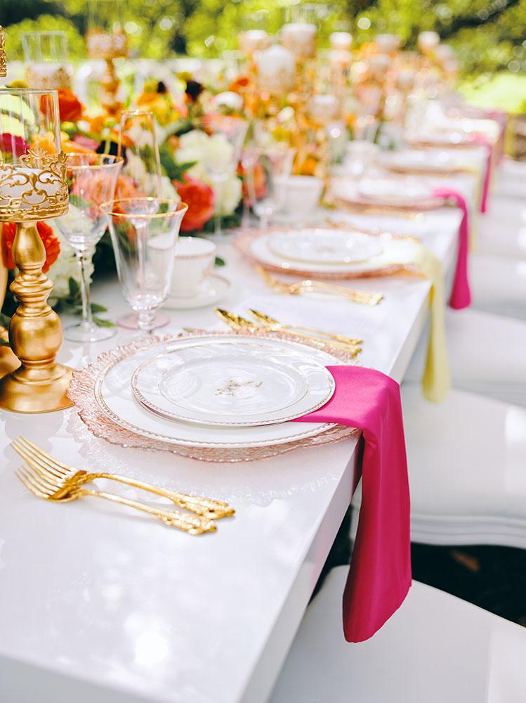 outdoor wedding reception - white chairs - pink napkins, charger plates, gold tableware, floral table runner, wedding cake, pink, yellow, orange, bouquet, houstonian, royal luxury events