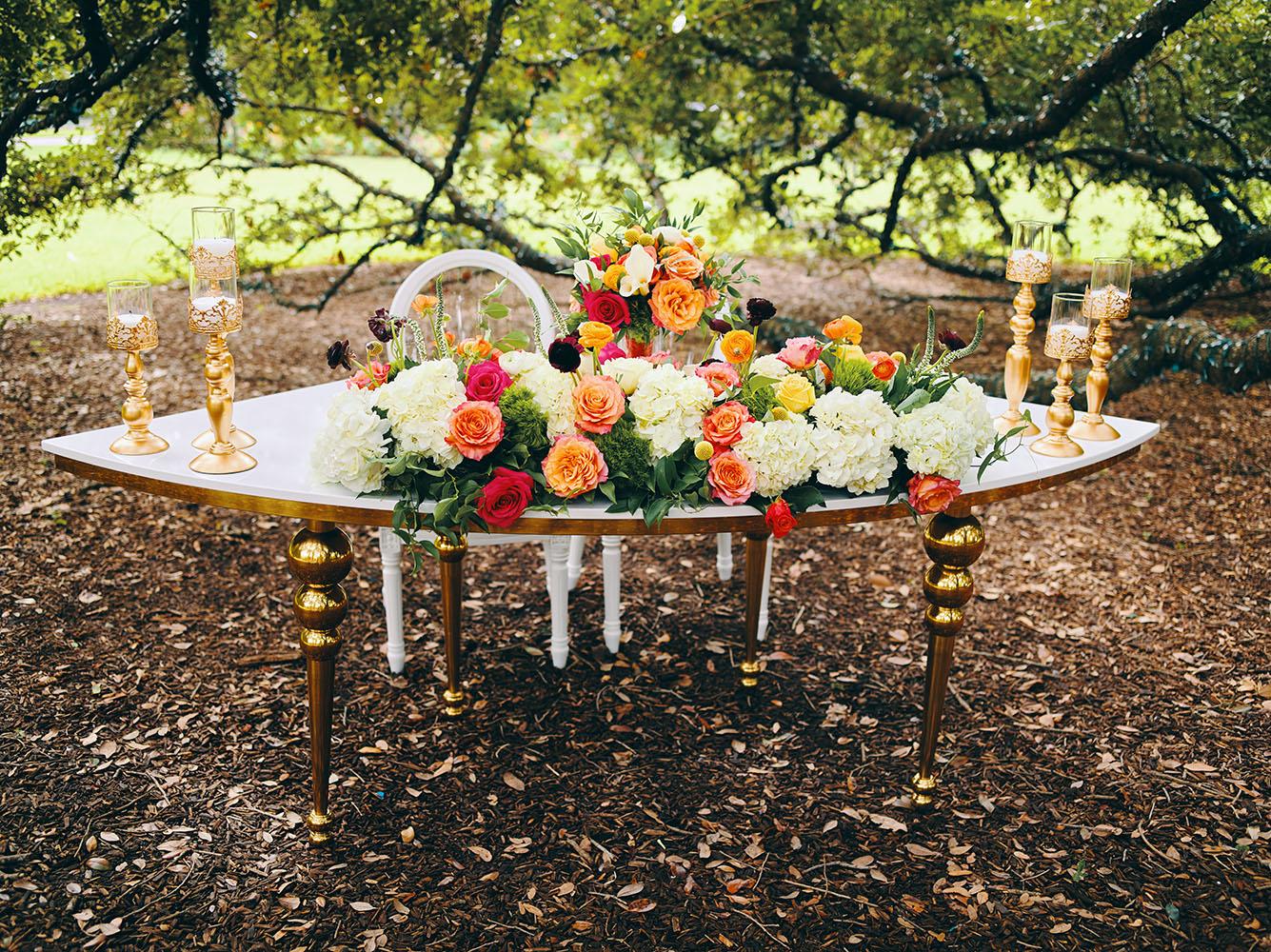 outdoor wedding reception - white chairs - pink napkins, charger plates, gold tableware, floral table runner, wedding cake, pink, yellow, orange, bouquet, houstonian, royal luxury events