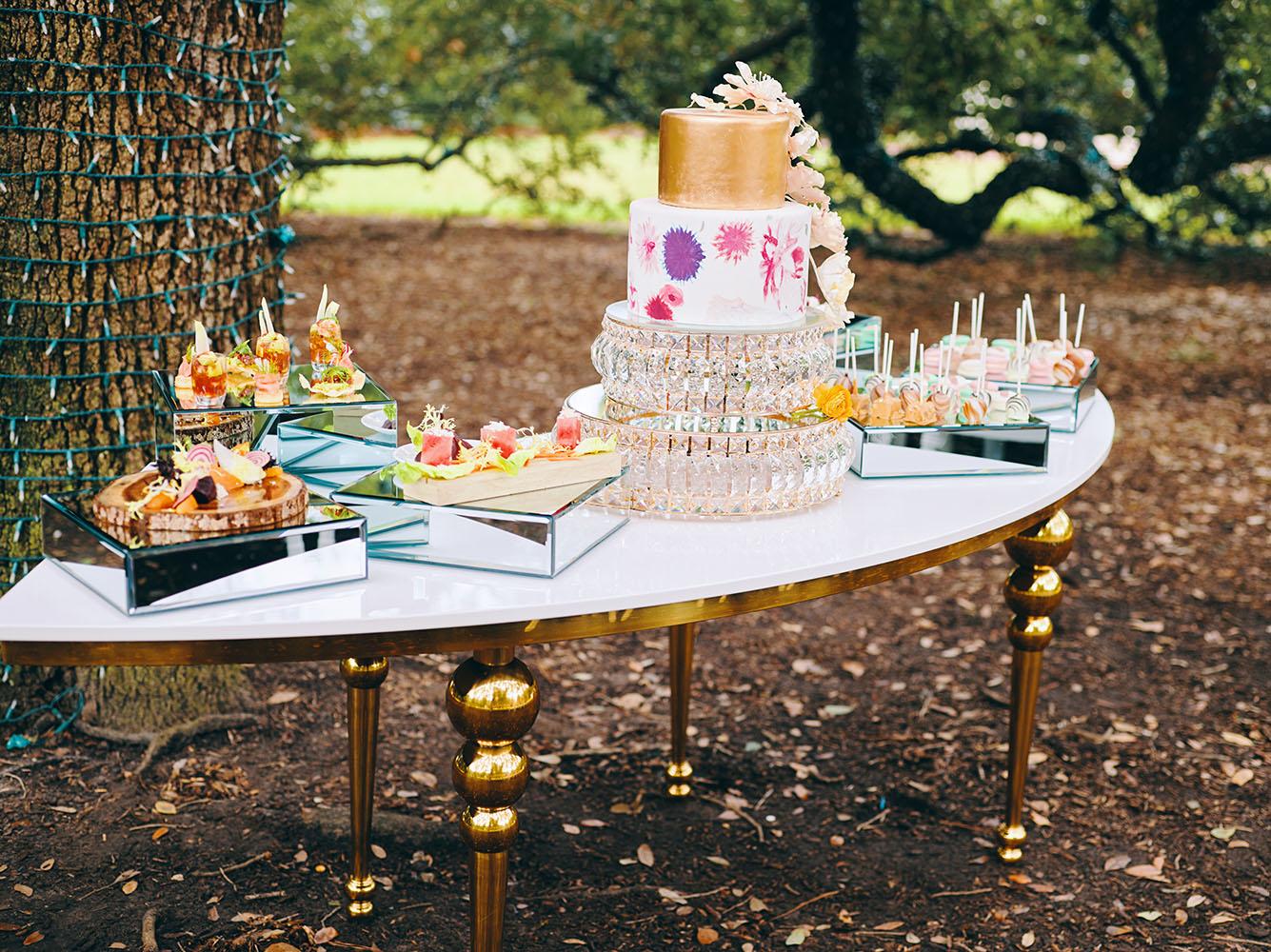 outdoor wedding reception - white chairs - pink napkins, charger plates, gold tableware, floral table runner, wedding cake, pink, yellow, orange, bouquet, houstonian, royal luxury events