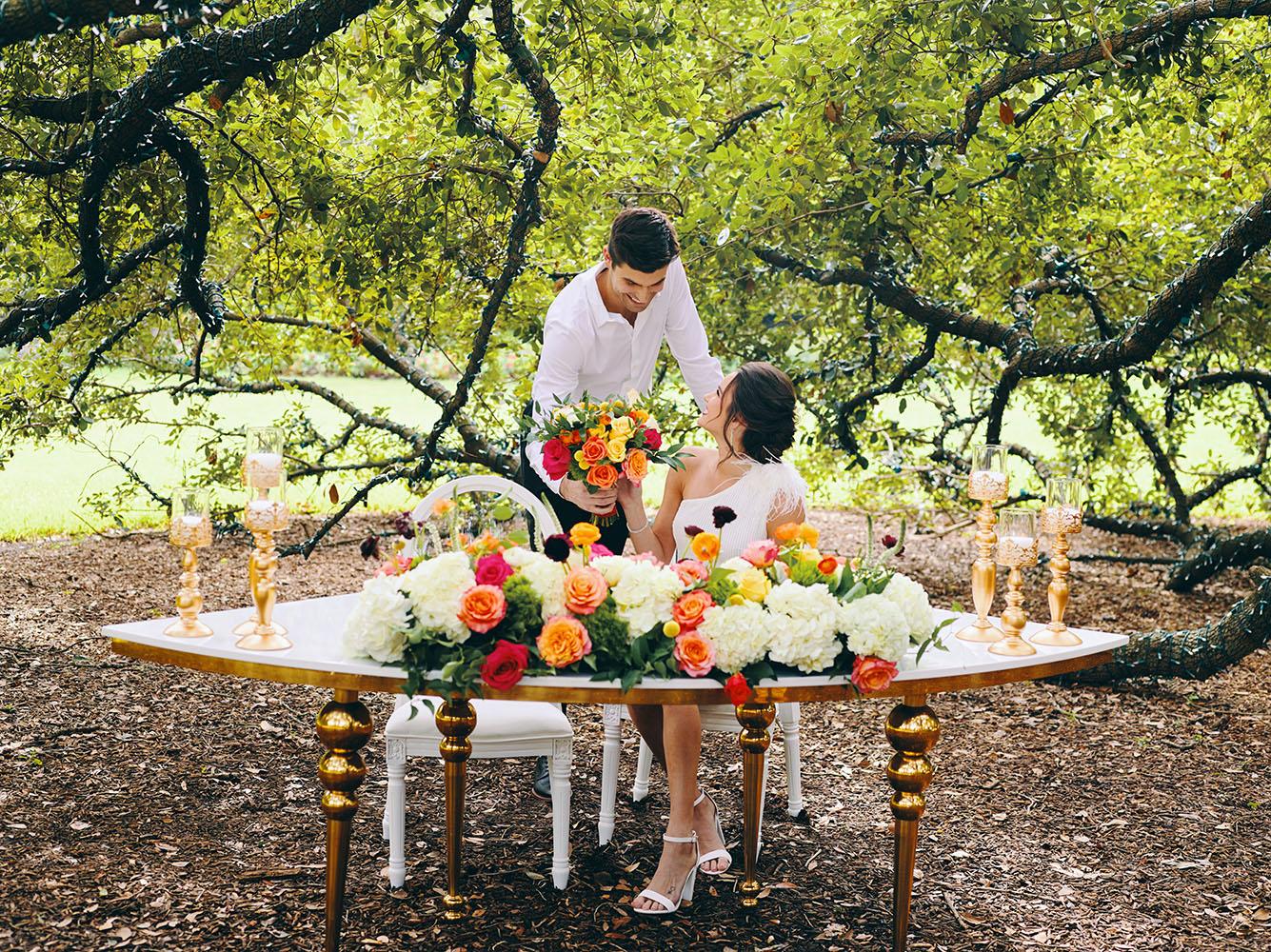 outdoor wedding reception - white chairs - pink napkins, charger plates, gold tableware, floral table runner, wedding cake, pink, yellow, orange, bouquet, houstonian, royal luxury events