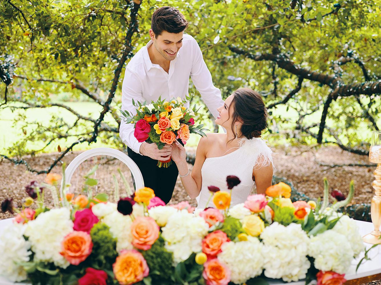 outdoor wedding reception - white chairs - pink napkins, charger plates, gold tableware, floral table runner, wedding cake, pink, yellow, orange, bouquet, houstonian, royal luxury events