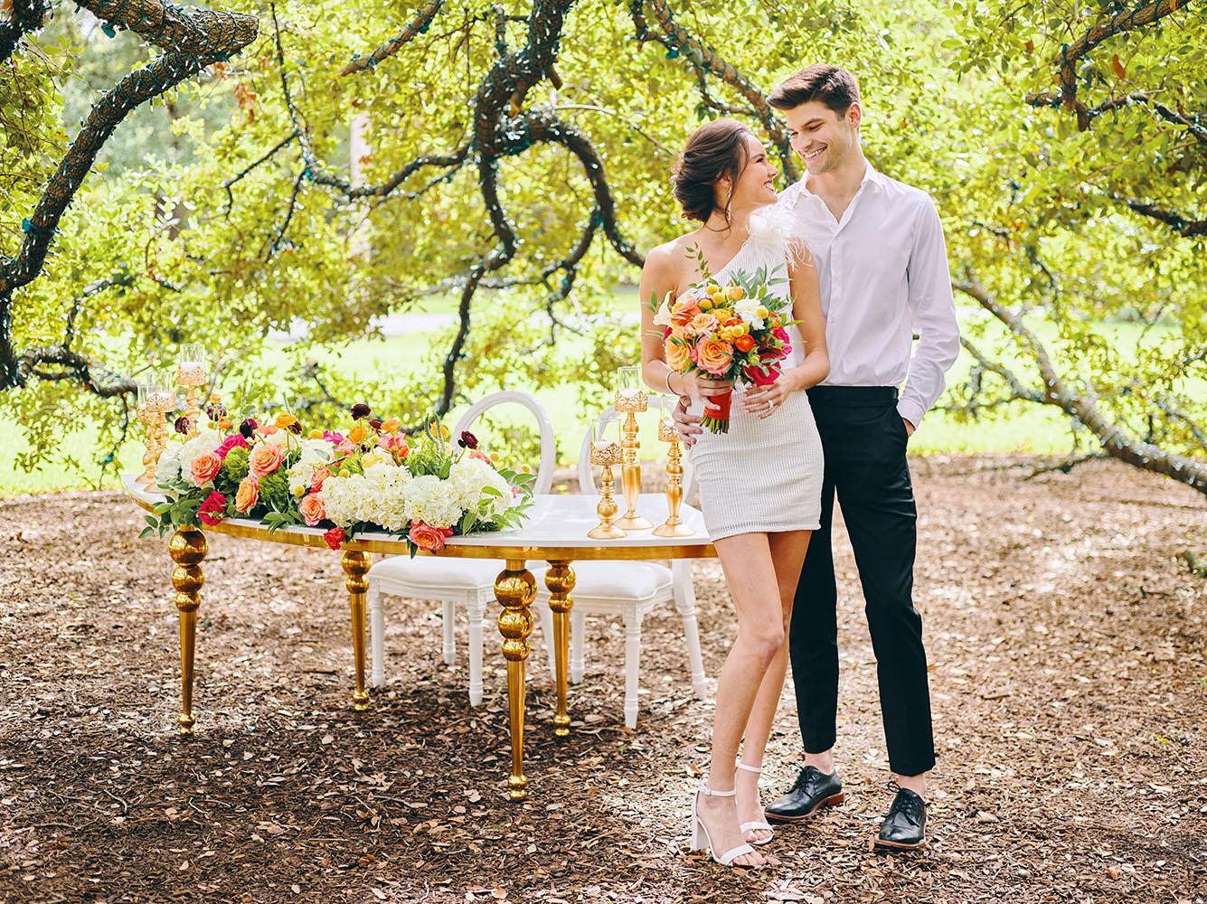outdoor wedding reception - white chairs - pink napkins, charger plates, gold tableware, floral table runner, wedding cake, pink, yellow, orange, bouquet, houstonian, royal luxury events