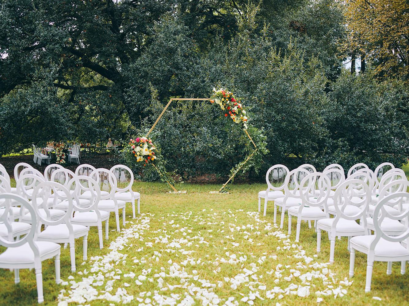 outdoor wedding ceremony - hexagon arch - bright florals - white chairs - houstonian hotel