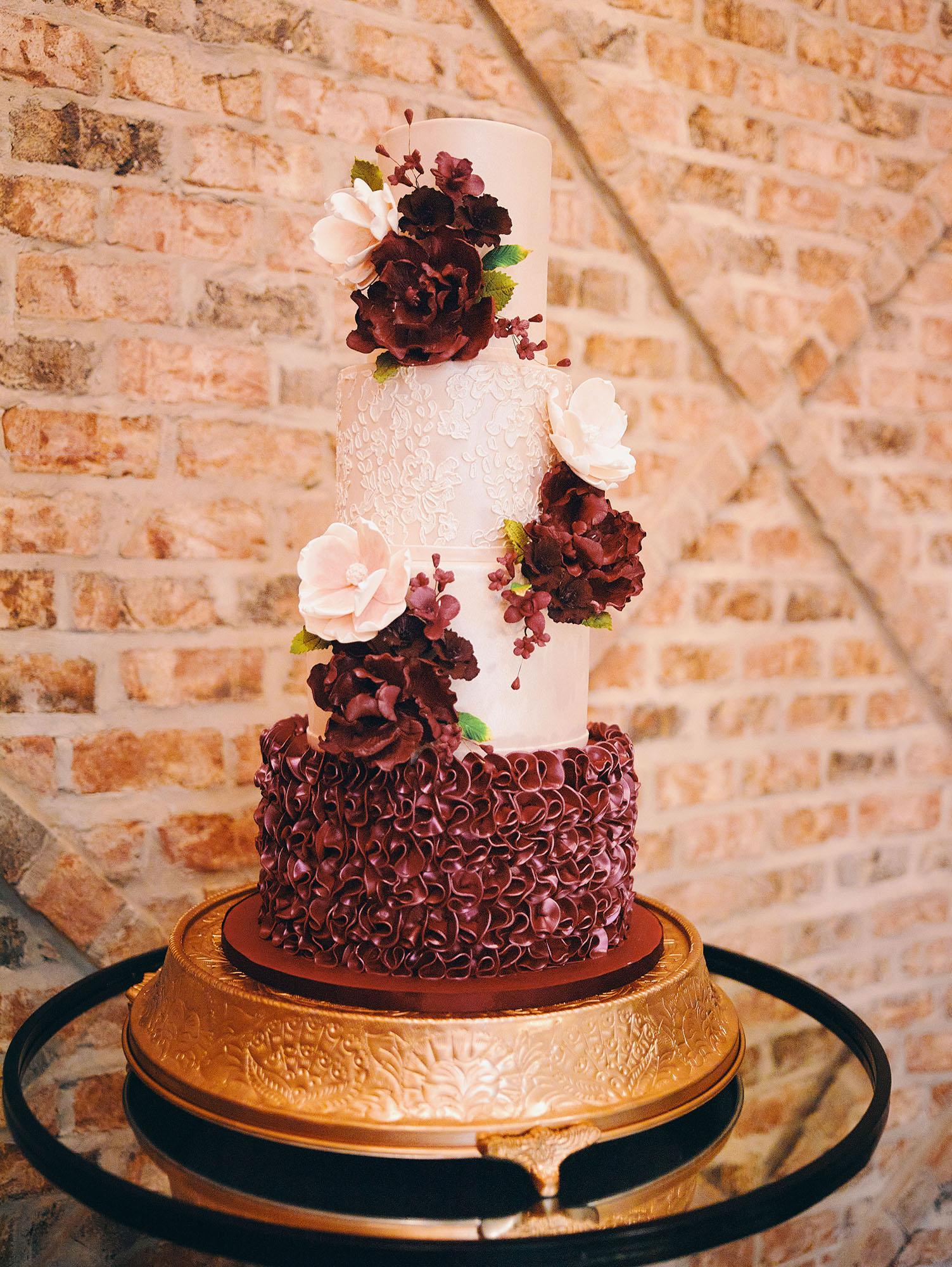 luxurious indoor wedding reception decor design, with red, yellow and orange floral designs, gold and black chairs, rectangular table, and a stunning bride and bridal bouquet.