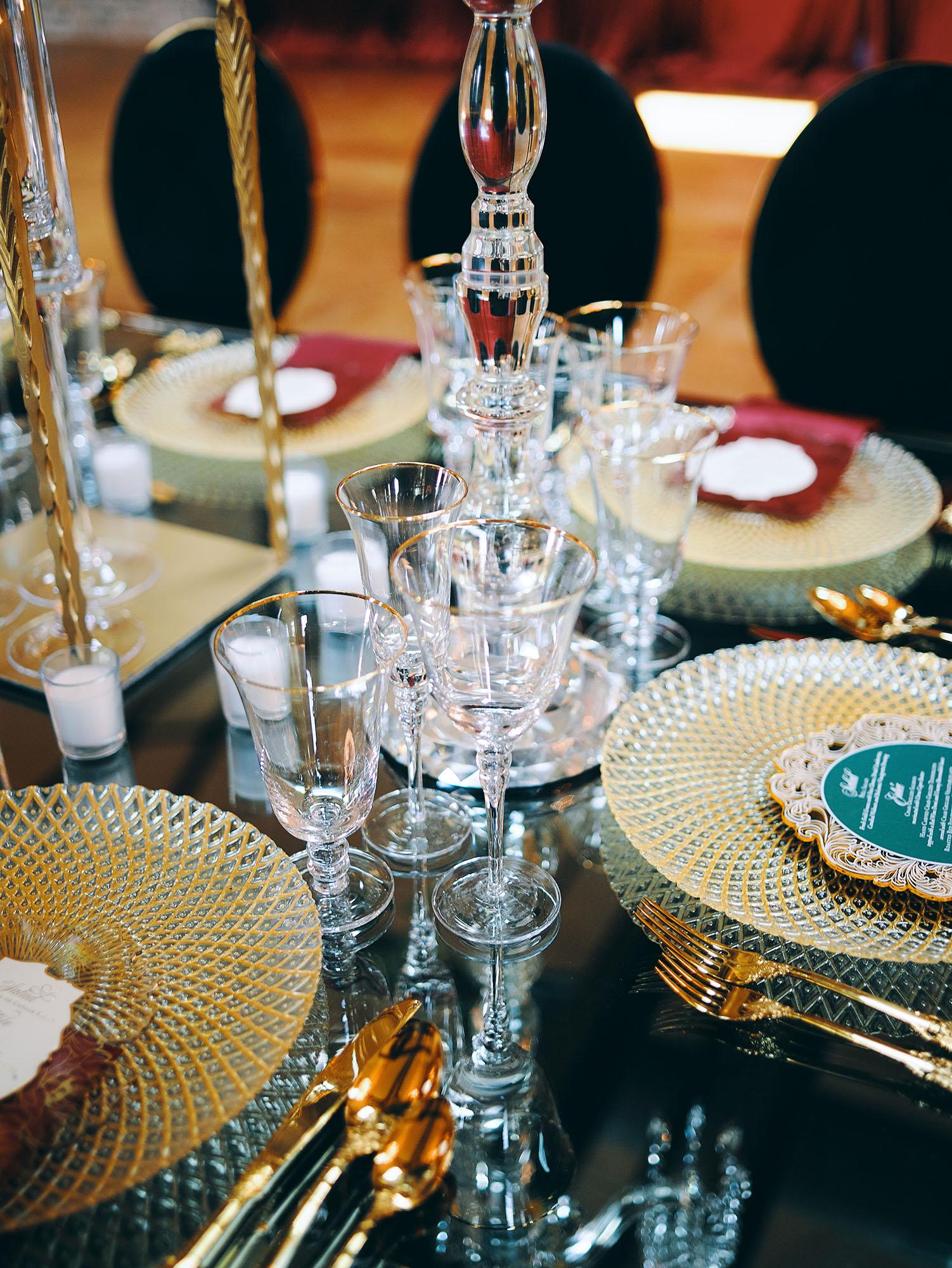 luxurious indoor wedding reception decor design, with red, yellow and orange floral designs, gold and black chairs, rectangular table, and a stunning bride and bridal bouquet.