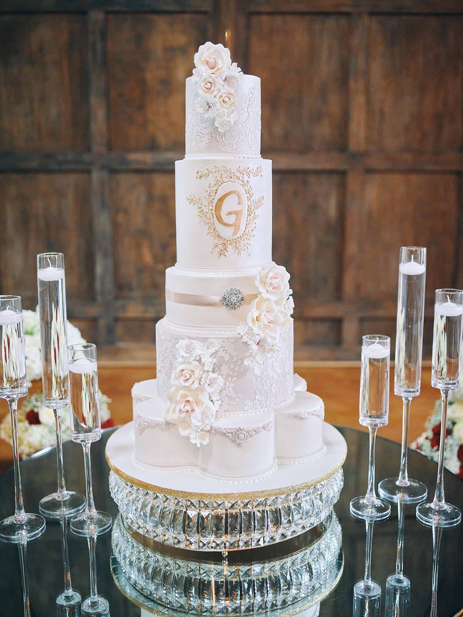 luxurious indoor wedding reception decor design, with red, and white floral designs, gold and white curved tables, gold chairs, and a stunning bride and bridal bouquet.