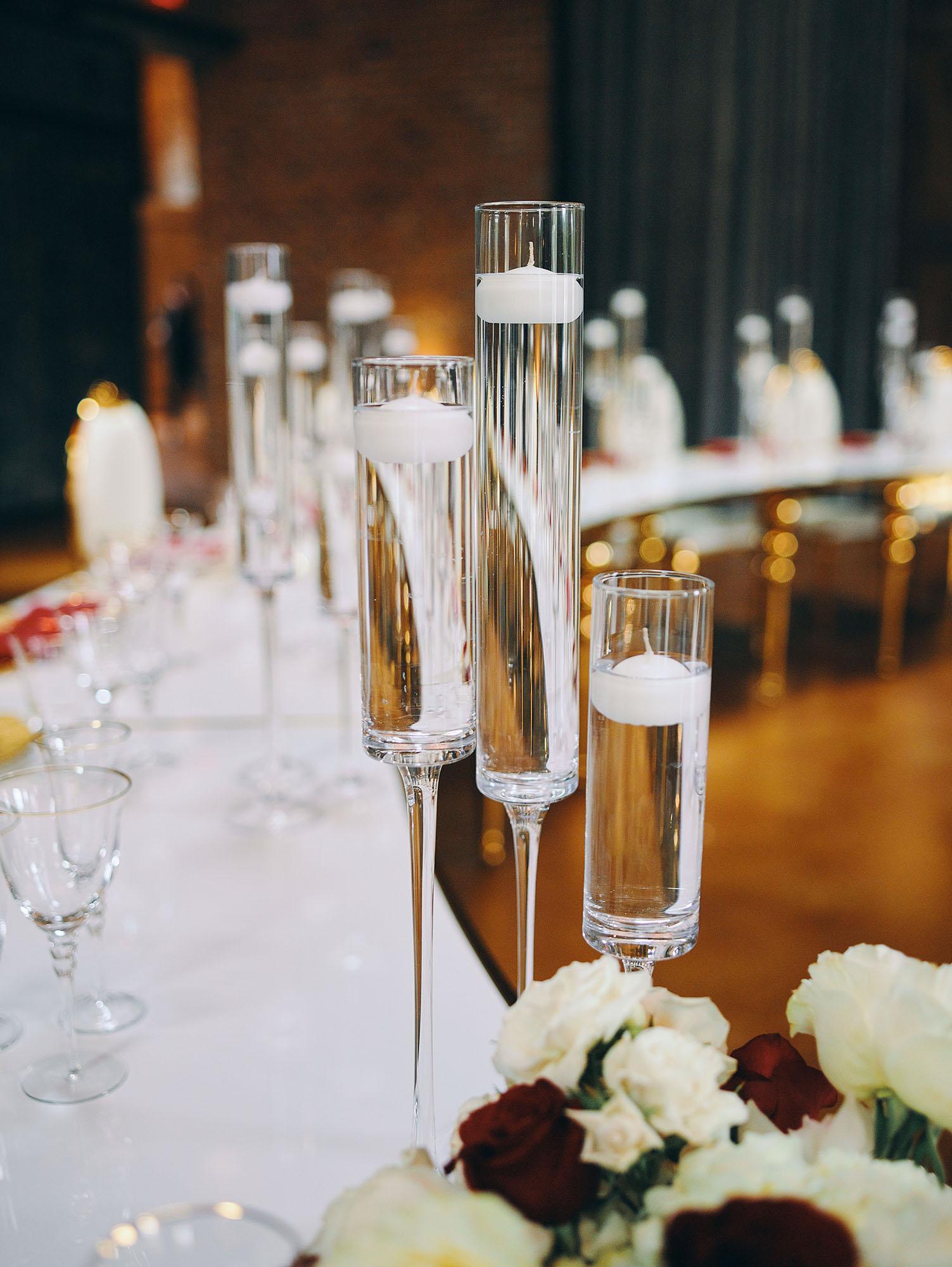 luxurious indoor wedding reception decor design, with red, and white floral designs, gold and white curved tables, gold chairs, and a stunning bride and bridal bouquet.