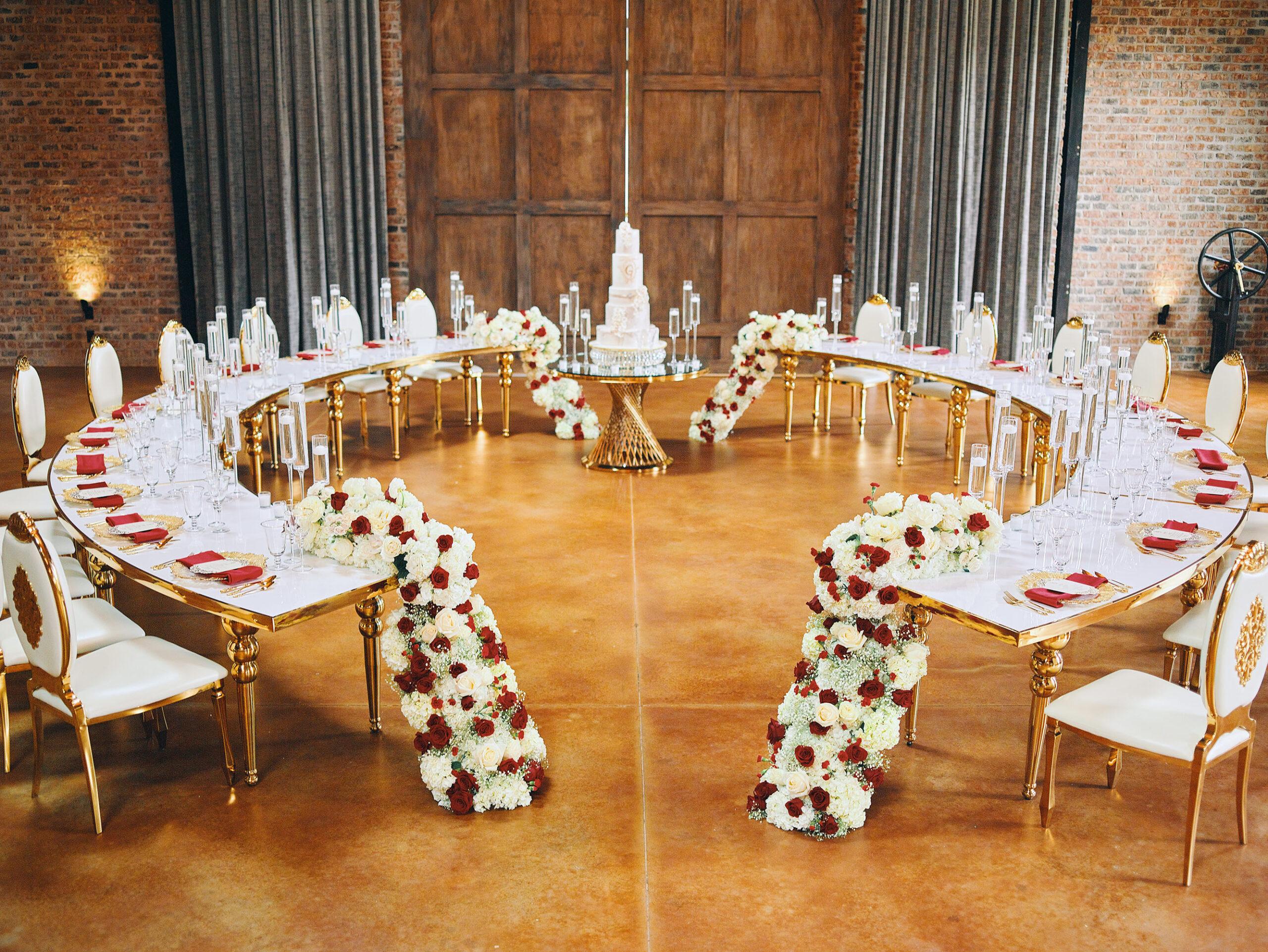 luxurious indoor wedding reception decor design, with red, and white floral designs, gold and white curved tables, gold chairs, and a stunning bride and bridal bouquet. luxurious indoor wedding reception decor design, with red, and white floral designs, gold and white curved tables, gold chairs, and a stunning bride and bridal bouquet. by royal luxury events in houston, texas