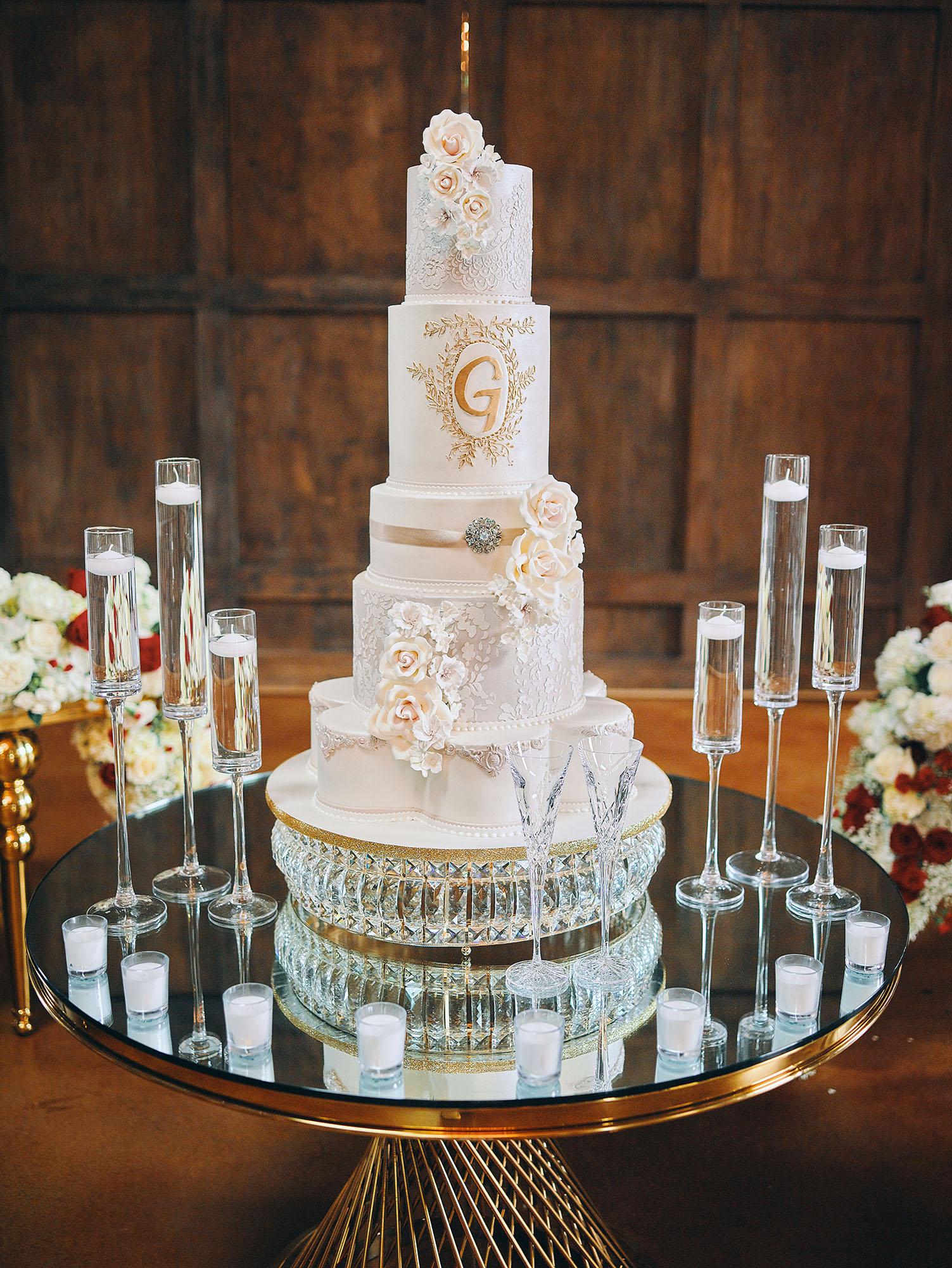 luxurious indoor wedding reception decor design, with red, and white floral designs, gold and white curved tables, gold chairs, and a stunning bride and bridal bouquet.