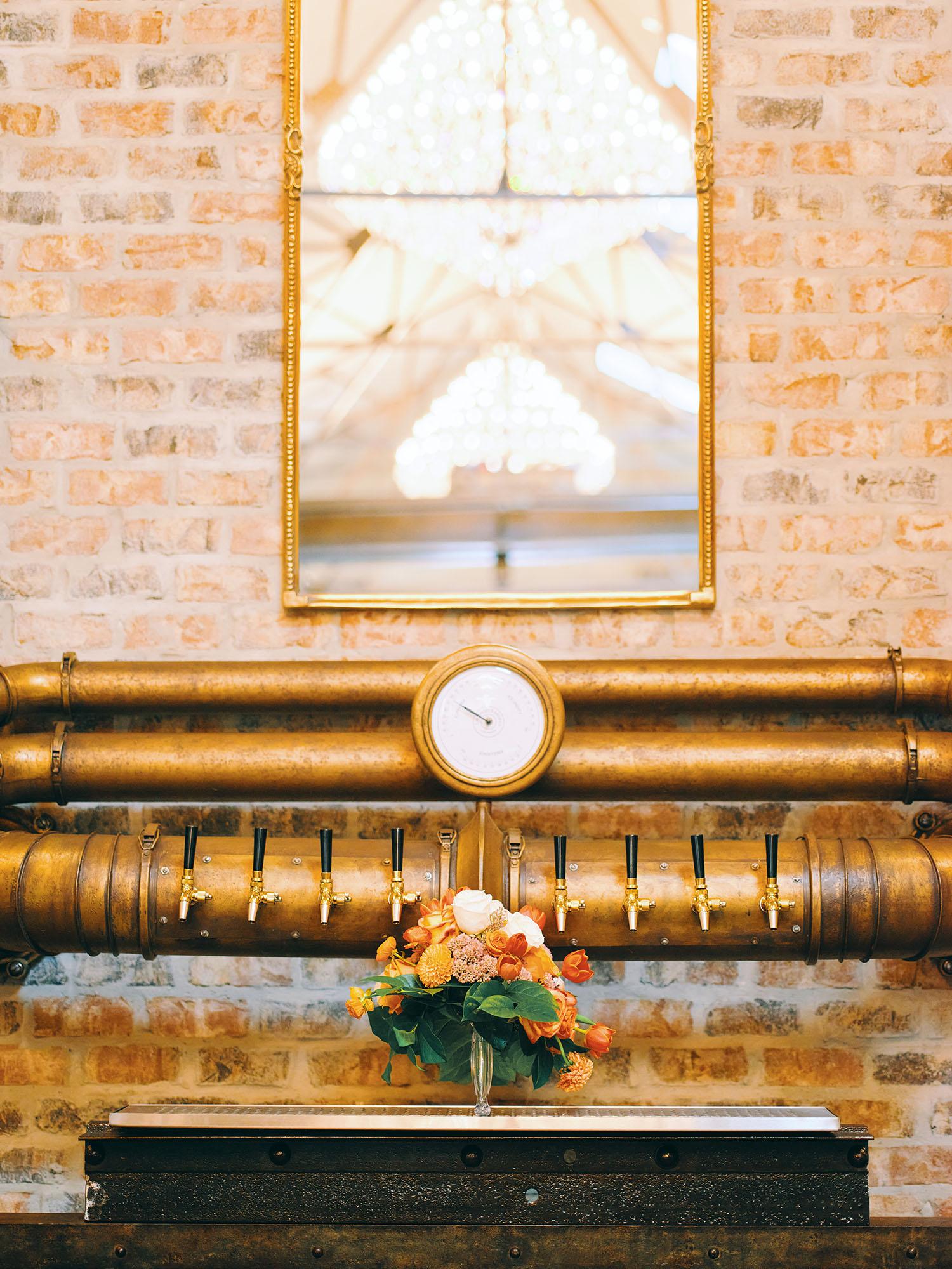 luxurious indoor wedding reception decor design, with red, yellow and orange floral designs, gold and black chairs, rectangular table, and a stunning bride and bridal bouquet.