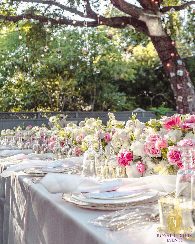 intimate backyard wedding decor featured pastel florals, white chairs, a greenery wall, and many other unique details