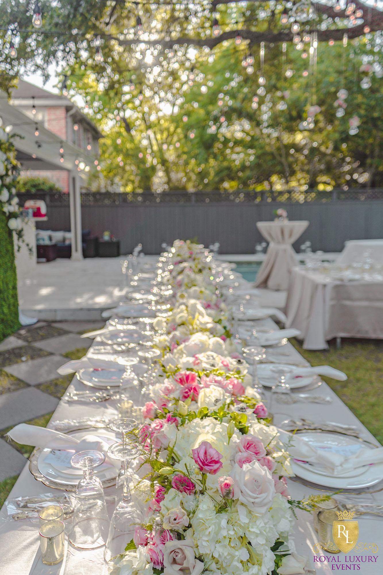 long floral table runner with charger plates, pink flowers, in a backyard wedding