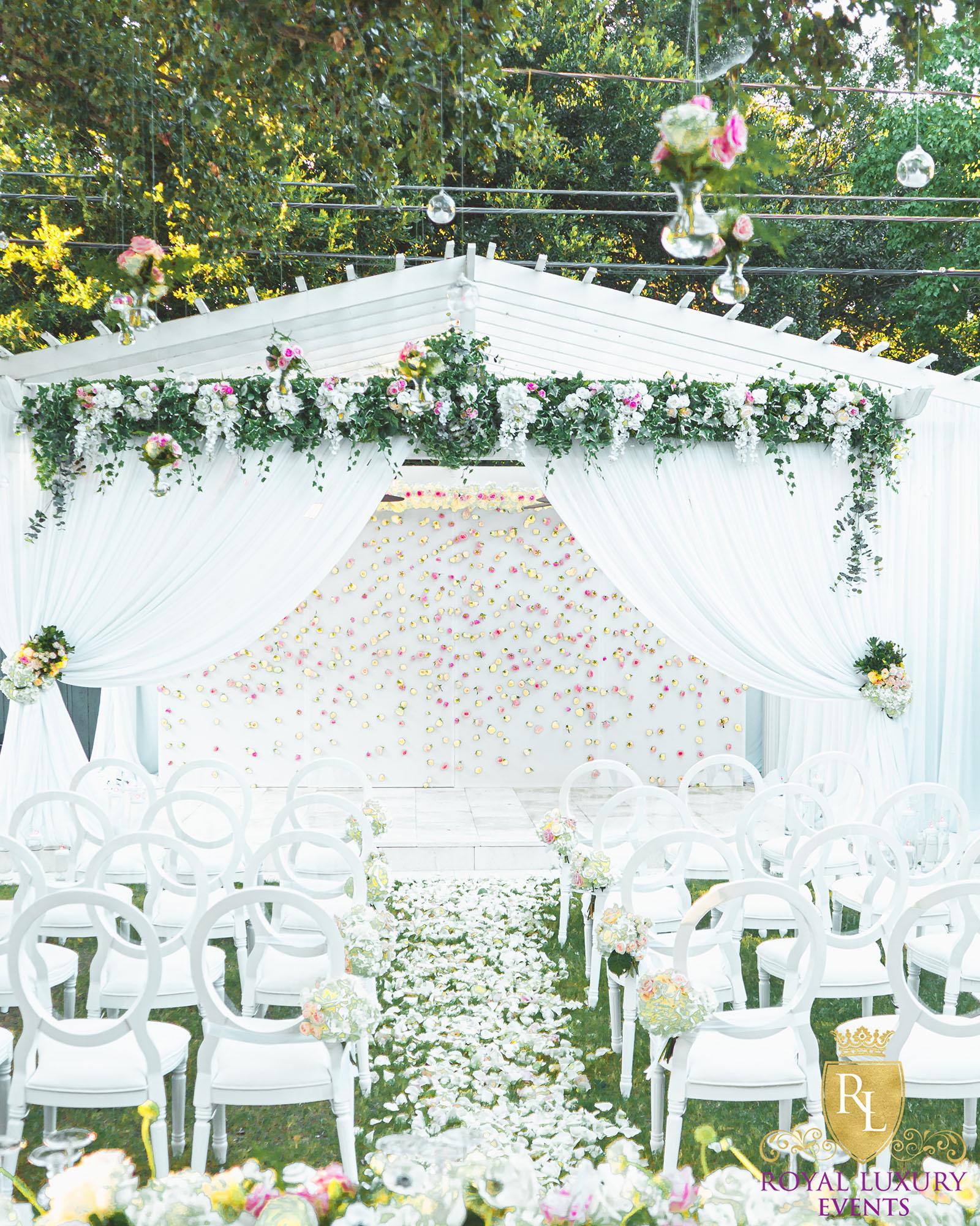 intimate backyard wedding decor featured pastel florals, white chairs, a greenery wall, and many other unique details - houston wedding decor