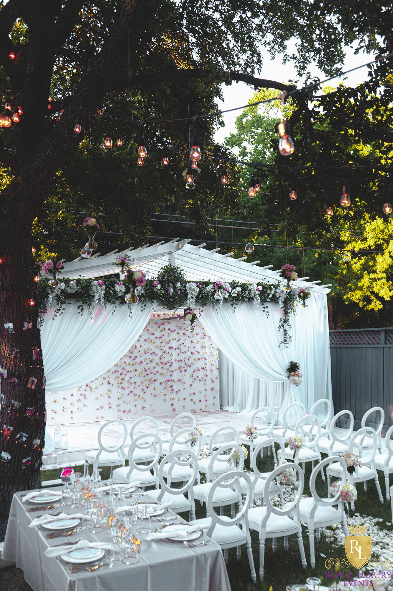 intimate backyard wedding decor featured pastel florals, white chairs, a greenery wall, and many other unique details - houston wedding decor
