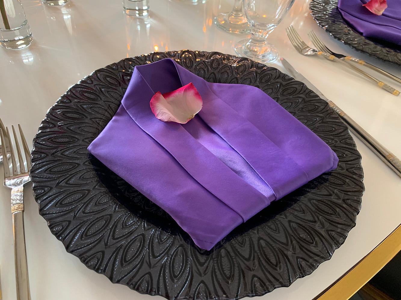 rehearsal dinner - black chairs - purple napkins - pink flowers - backdrop - bougainvilleas - serpentine tables - black charger plates