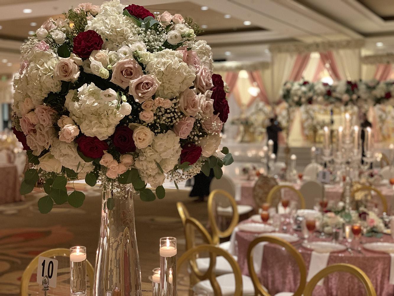 View Michelle and Anzon's luxury wedding at Houston Marriott Sugar Land, featuring pink white and red flowers with gold accented decor.