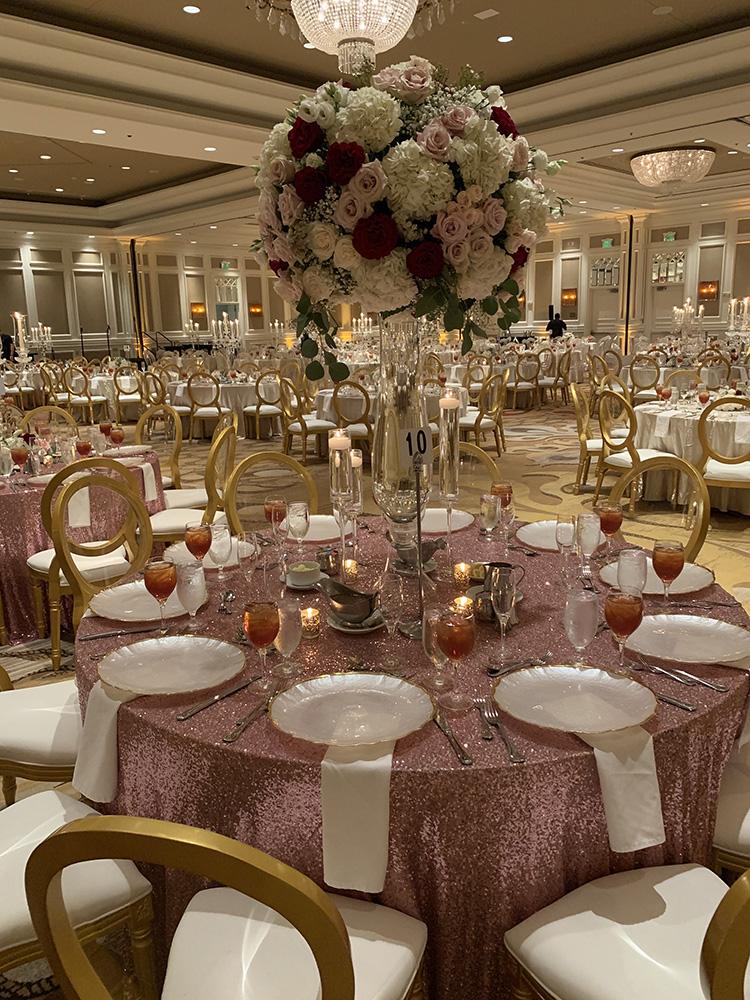 View Michelle and Anzon's luxury wedding at Houston Marriott Sugar Land, featuring pink white and red flowers with gold accented decor.
