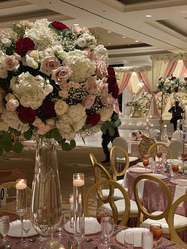 View Michelle and Anzon's luxury wedding at Houston Marriott Sugar Land, featuring pink white and red flowers with gold accented decor.
