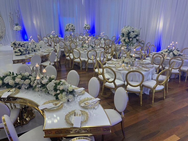 NOAH’s Event Venue. Featuring gold and white wedding decor, with blue uplighting.
