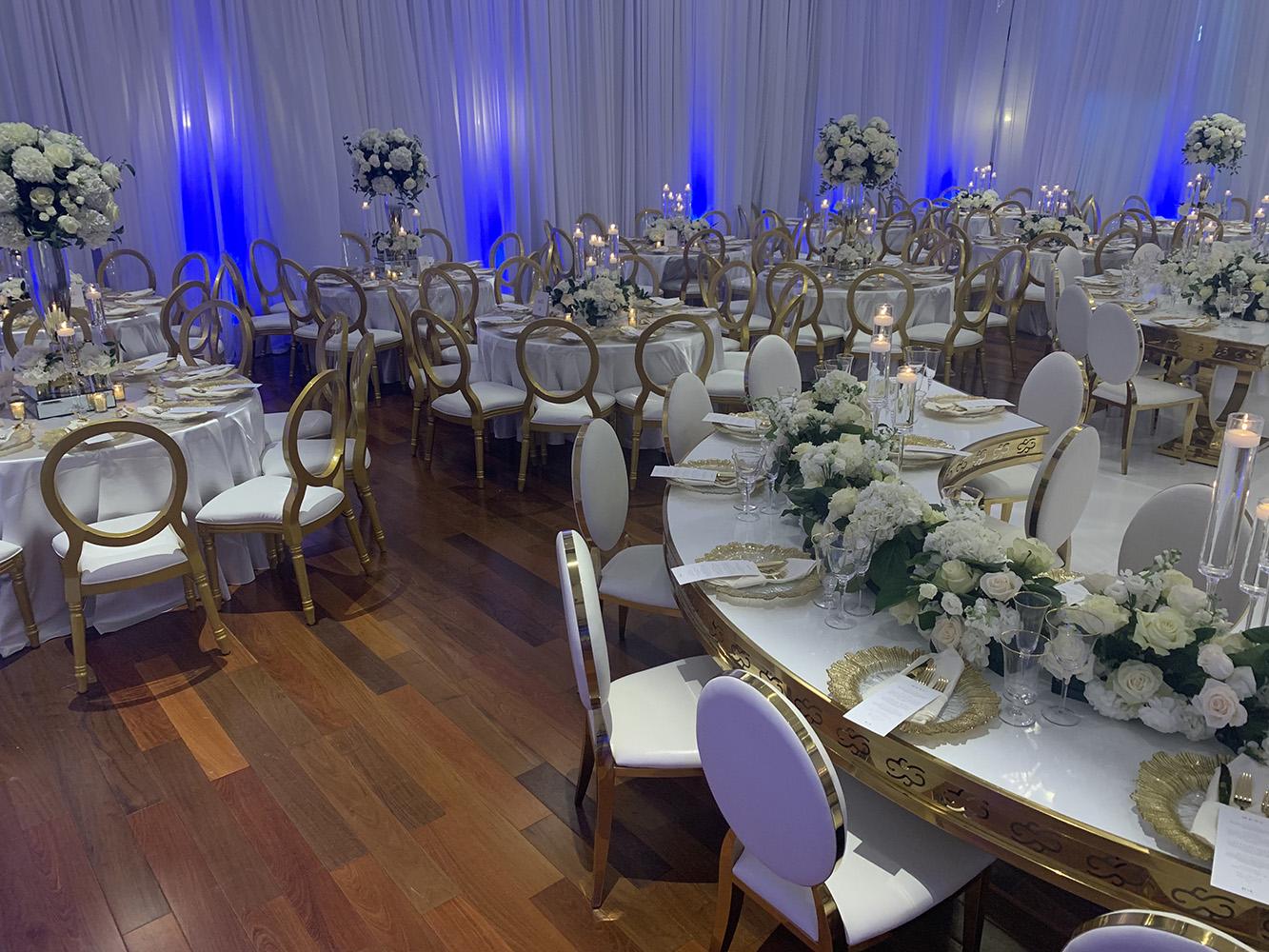 NOAH’s Event Venue. Featuring gold and white wedding decor, with blue uplighting.