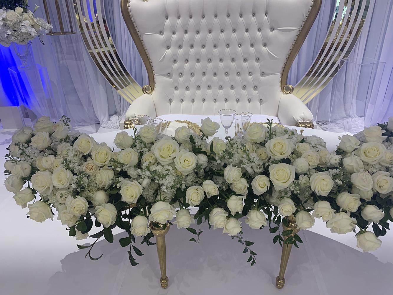 NOAH’s Event Venue. Featuring gold and white wedding decor, with blue uplighting.