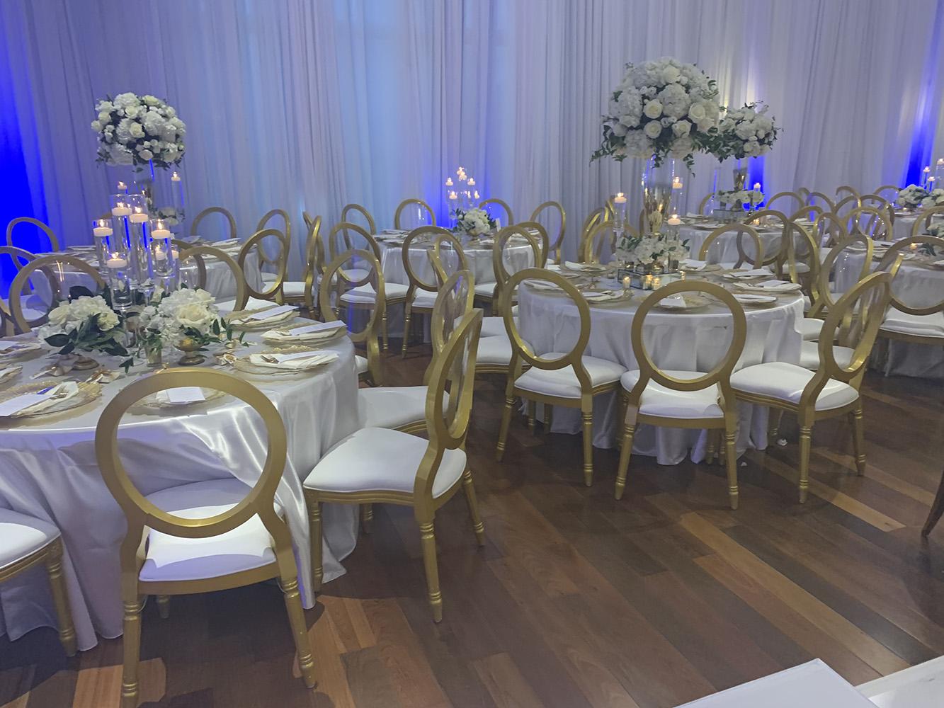 NOAH’s Event Venue. Featuring gold and white wedding decor, with blue uplighting.