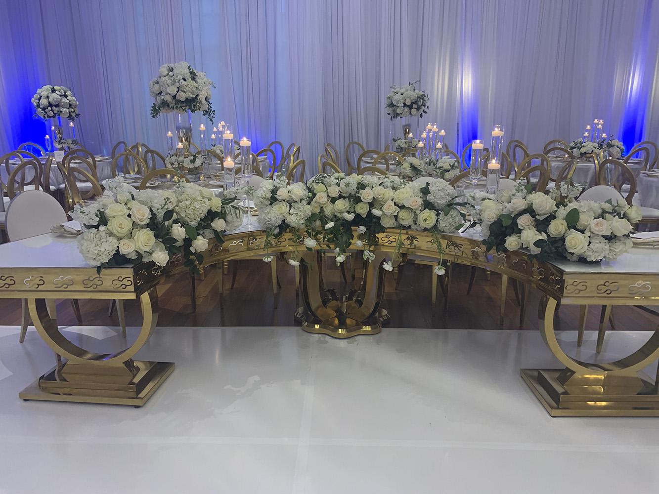 NOAH’s Event Venue. Featuring gold and white wedding decor, with blue uplighting.