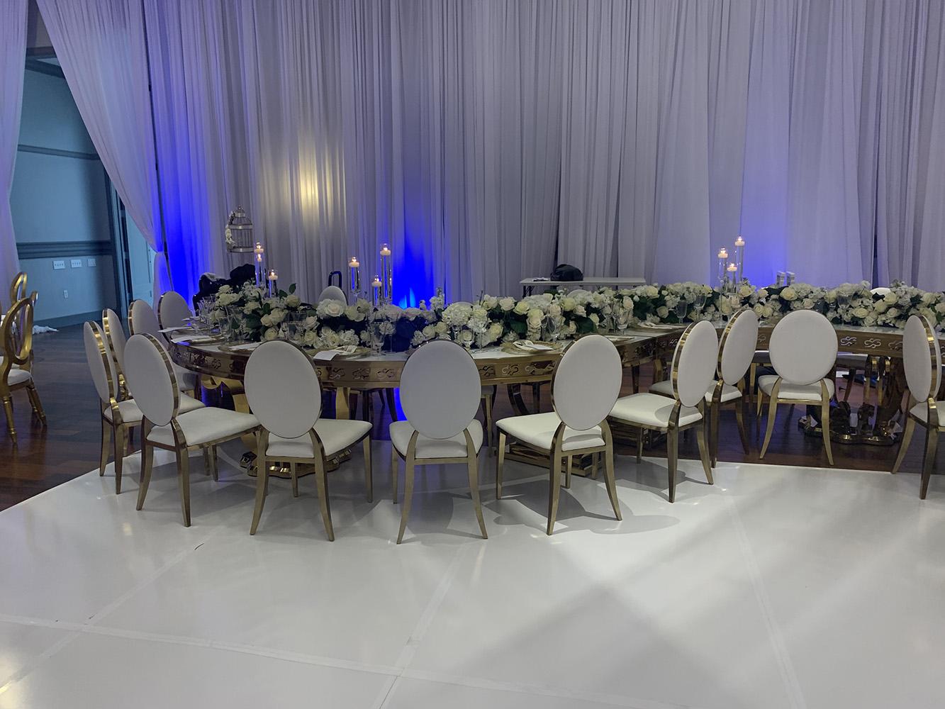 NOAH’s Event Venue. Featuring gold and white wedding decor, with blue uplighting.