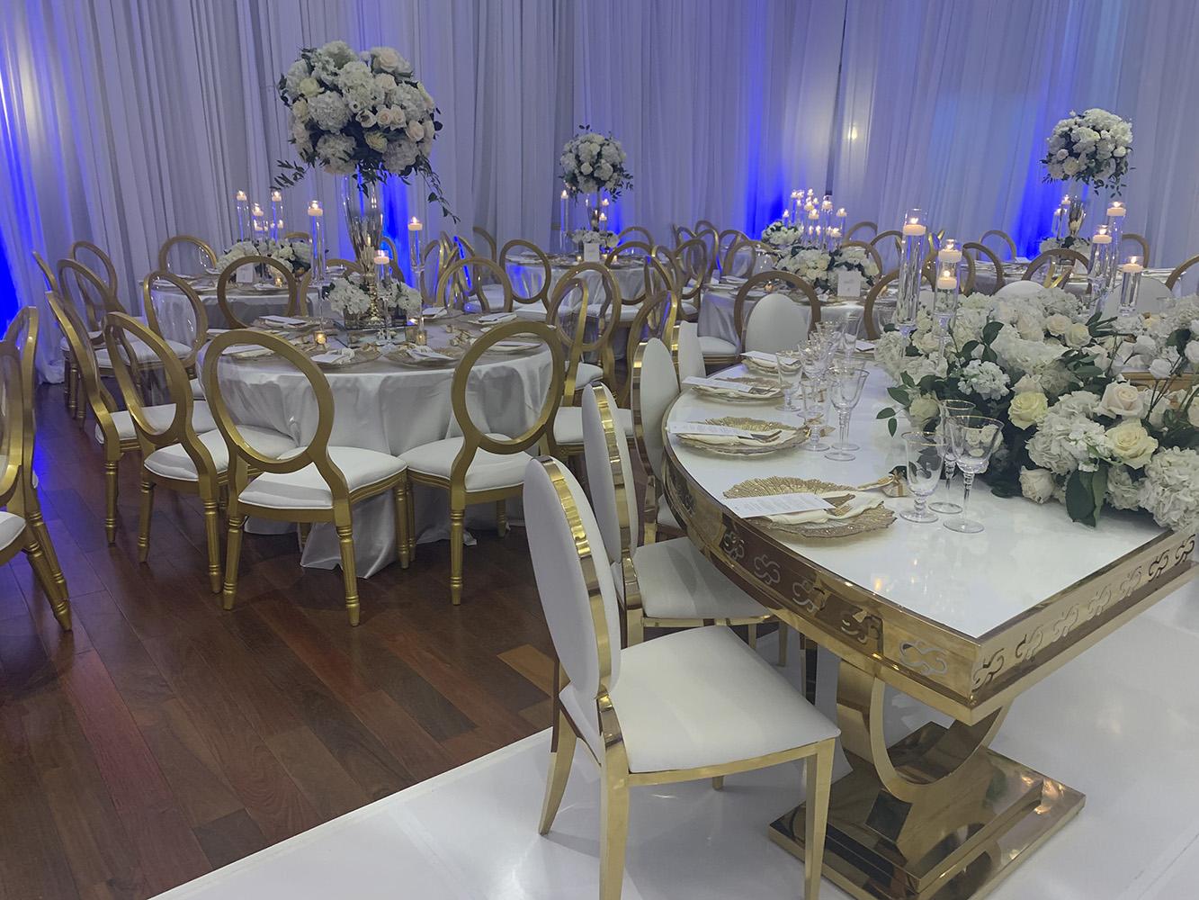 NOAH’s Event Venue. Featuring gold and white wedding decor, with blue uplighting.