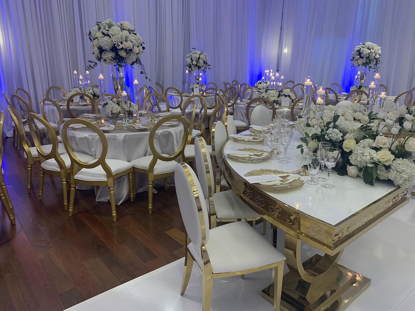 NOAH’s Event Venue. Featuring gold and white wedding decor, with blue uplighting.