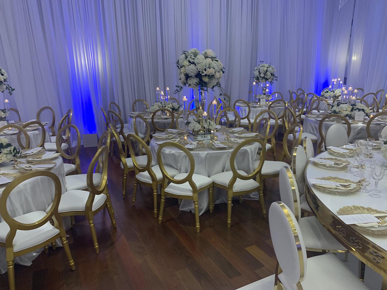 NOAH’s Event Venue. Featuring gold and white wedding decor, with blue uplighting.