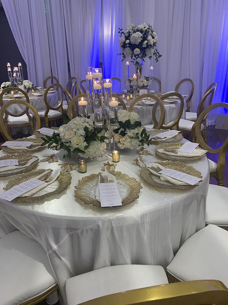 NOAH’s Event Venue. Featuring gold and white wedding decor, with blue uplighting.