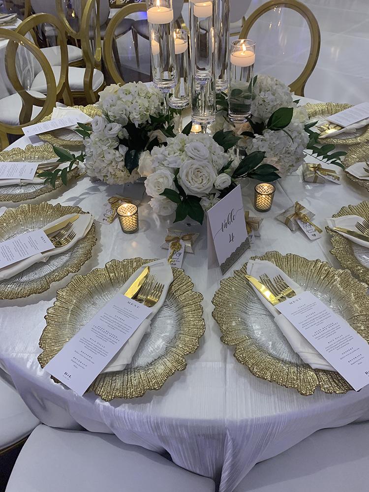 NOAH’s Event Venue. Featuring gold and white wedding decor, with blue uplighting.