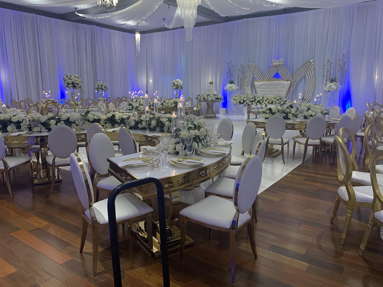NOAH’s Event Venue. Featuring gold and white wedding decor, with blue uplighting.