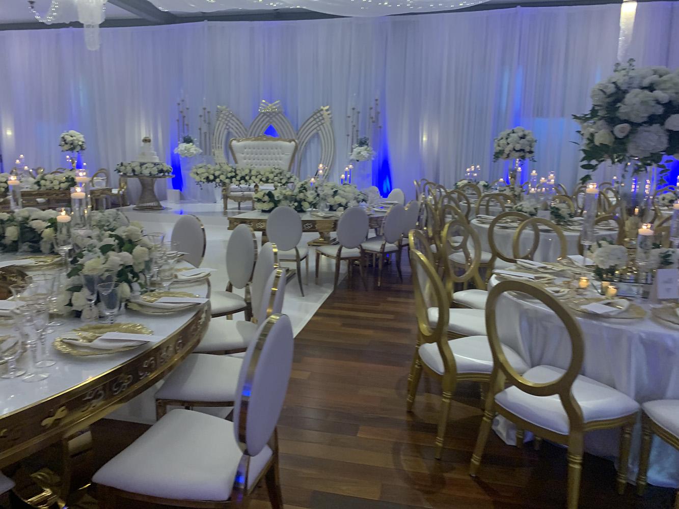 NOAH’s Event Venue. Featuring gold and white wedding decor, with blue uplighting.