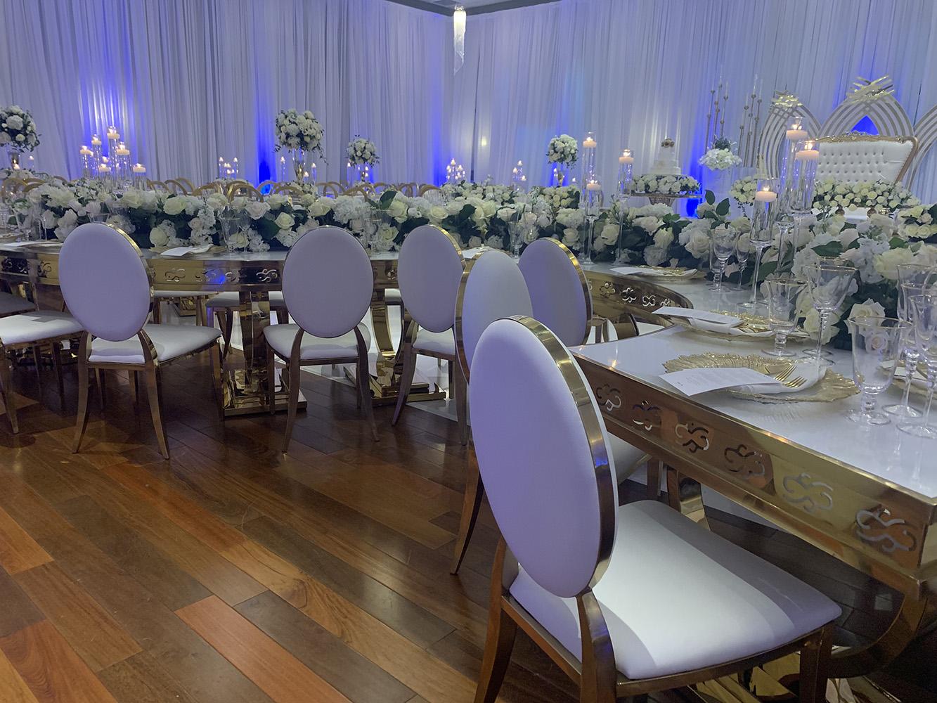 NOAH’s Event Venue. Featuring gold and white wedding decor, with blue uplighting.