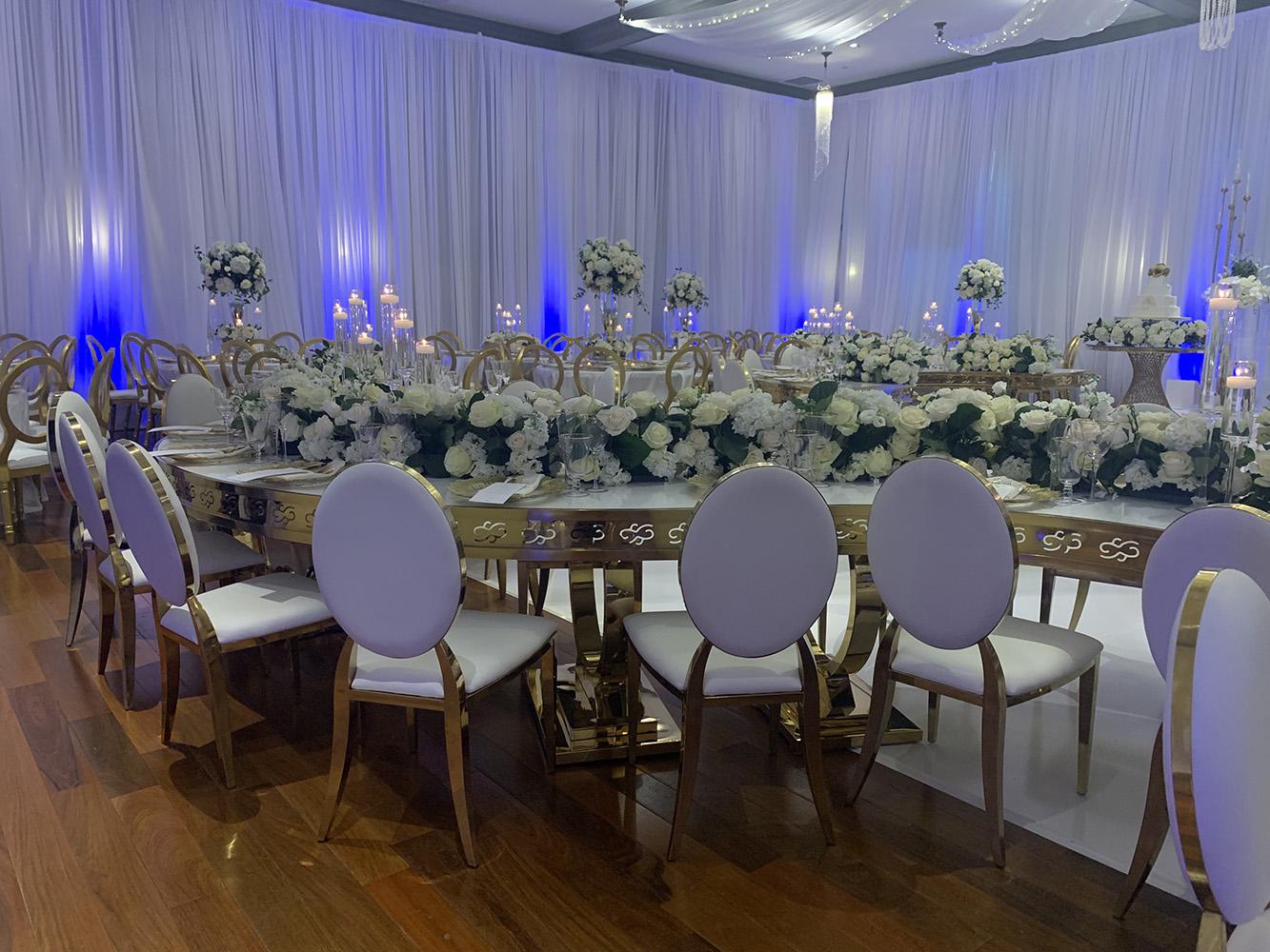 NOAH’s Event Venue. Featuring gold and white wedding decor, with blue uplighting.