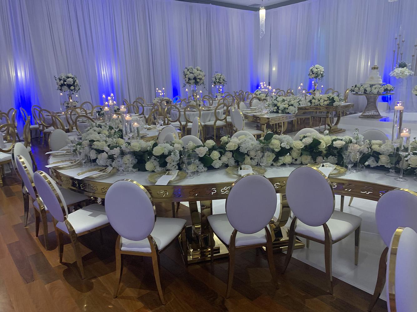 NOAH’s Event Venue. Featuring gold and white wedding decor, with blue uplighting.