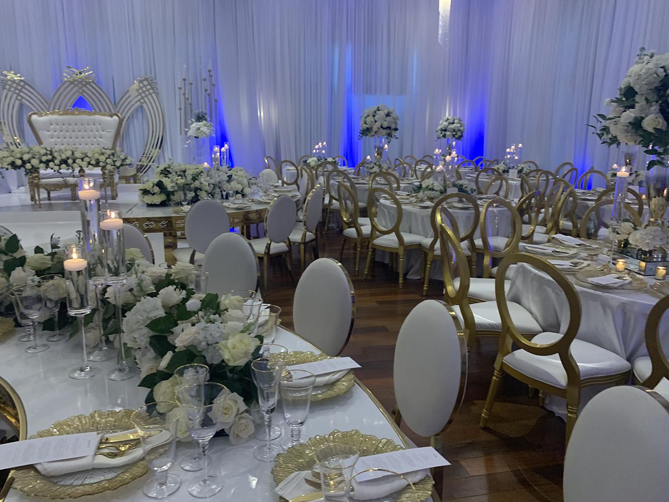 NOAH’s Event Venue. Featuring gold and white wedding decor, with blue uplighting.