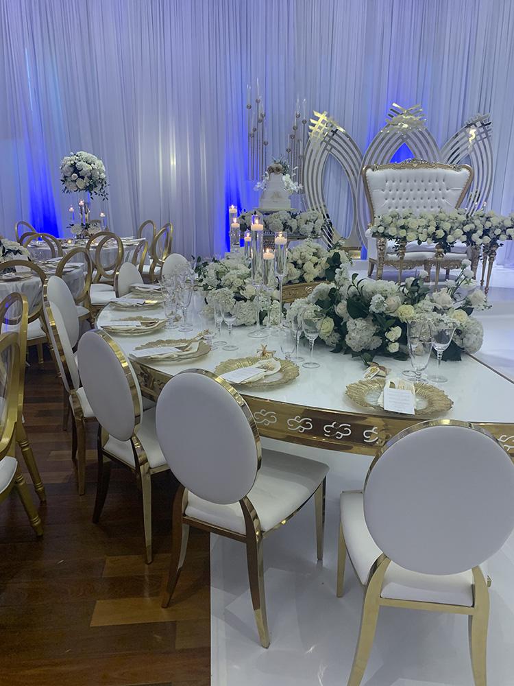 NOAH’s Event Venue. Featuring gold and white wedding decor, with blue uplighting.