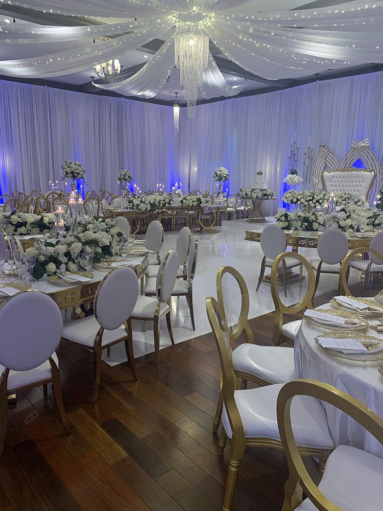 NOAH’s Event Venue. Featuring gold and white wedding decor, with blue uplighting.
