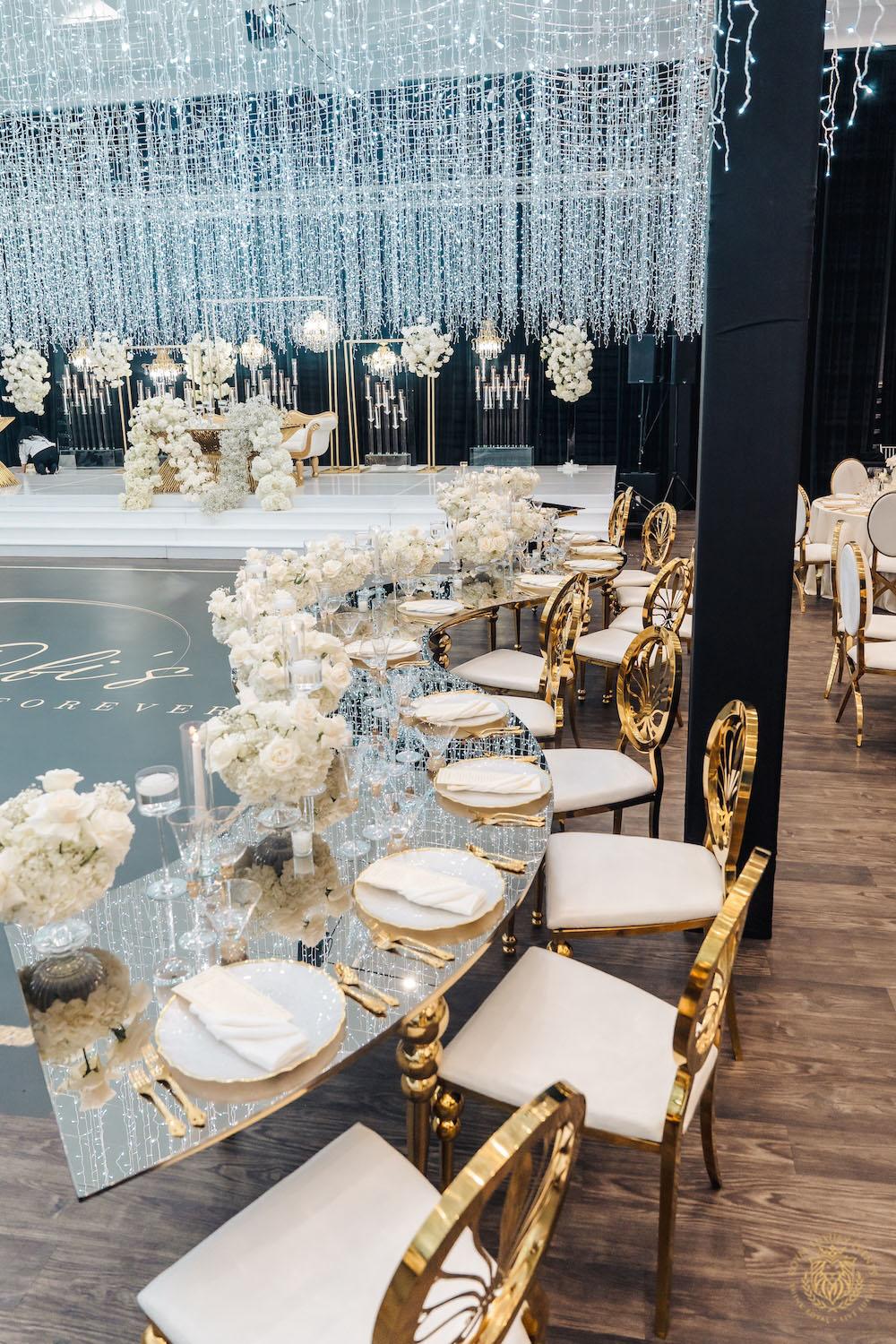 gold serpentine table, white and gold chair rentals, low floral centerpieces, wedding light installation