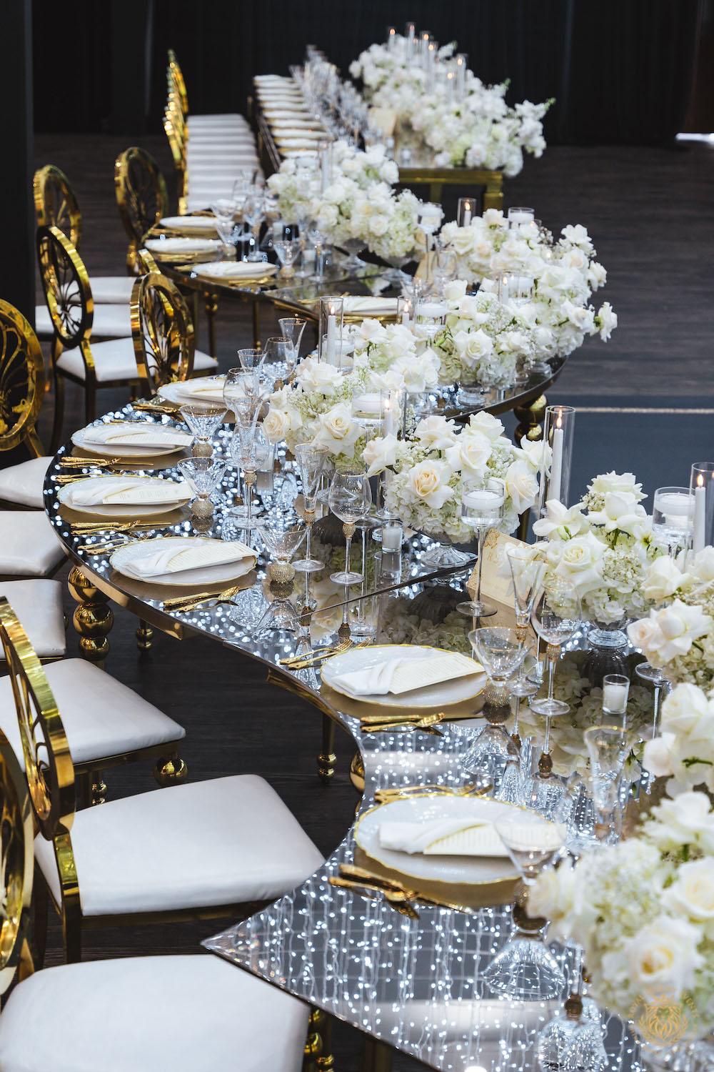 mirrored table top rental, gold and white chargers, wedding tablescape, luxury wedding place setting, serpentine table