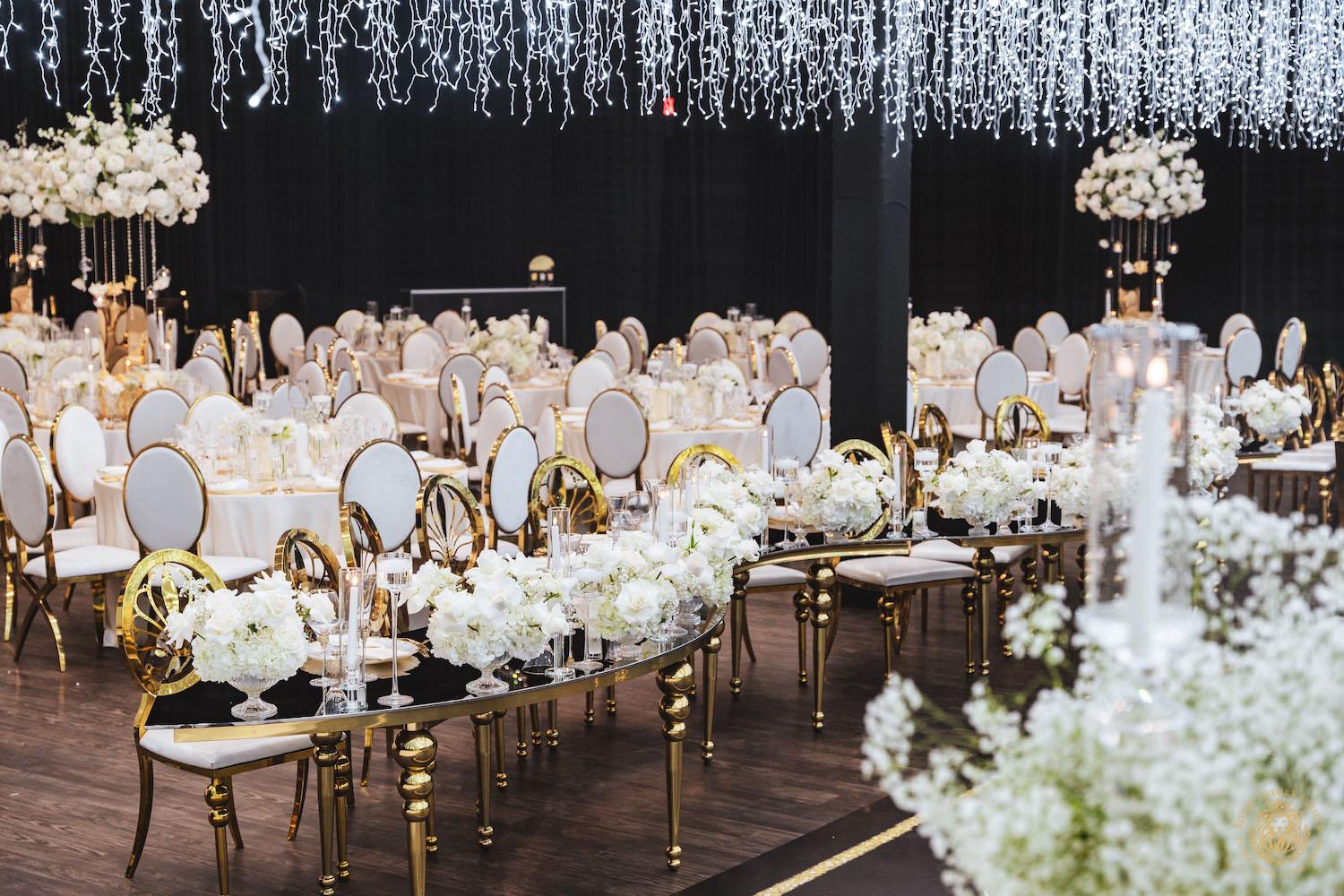 gold serpentine table, white and gold chair rentals, low floral centerpieces, wedding light installation